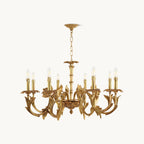 Antique brass candle-style chandelier from Clérachic on a plain white backdrop, with curved leaf-shaped arms and a hanging chain.