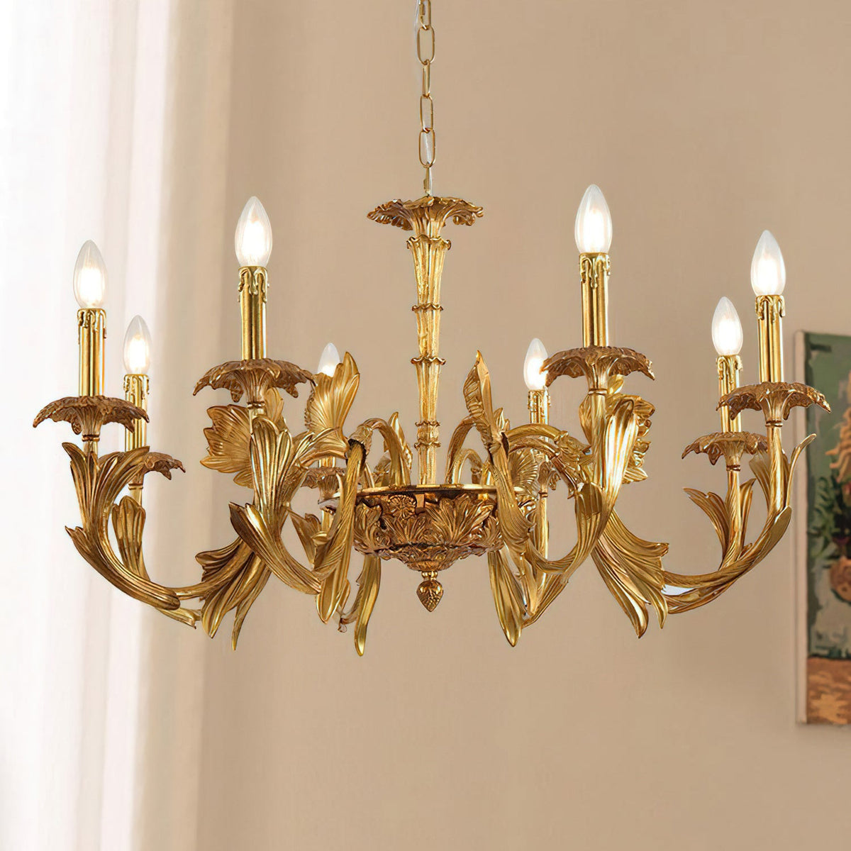 Low view of the lit Clérachic chandelier, its leafy brass arms curling out to candle-style bulbs against a soft cream wall.