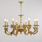 Straight-on view of the Clérachic antique brass chandelier on grey, candle-style bulbs lit above sweeping leaf arms.