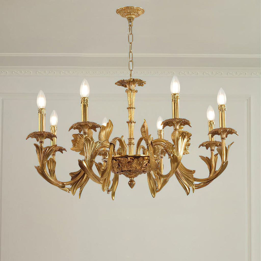 Clérachic brass chandelier hanging in a room with a white panelled wall and cornice, its candle bulbs lit.