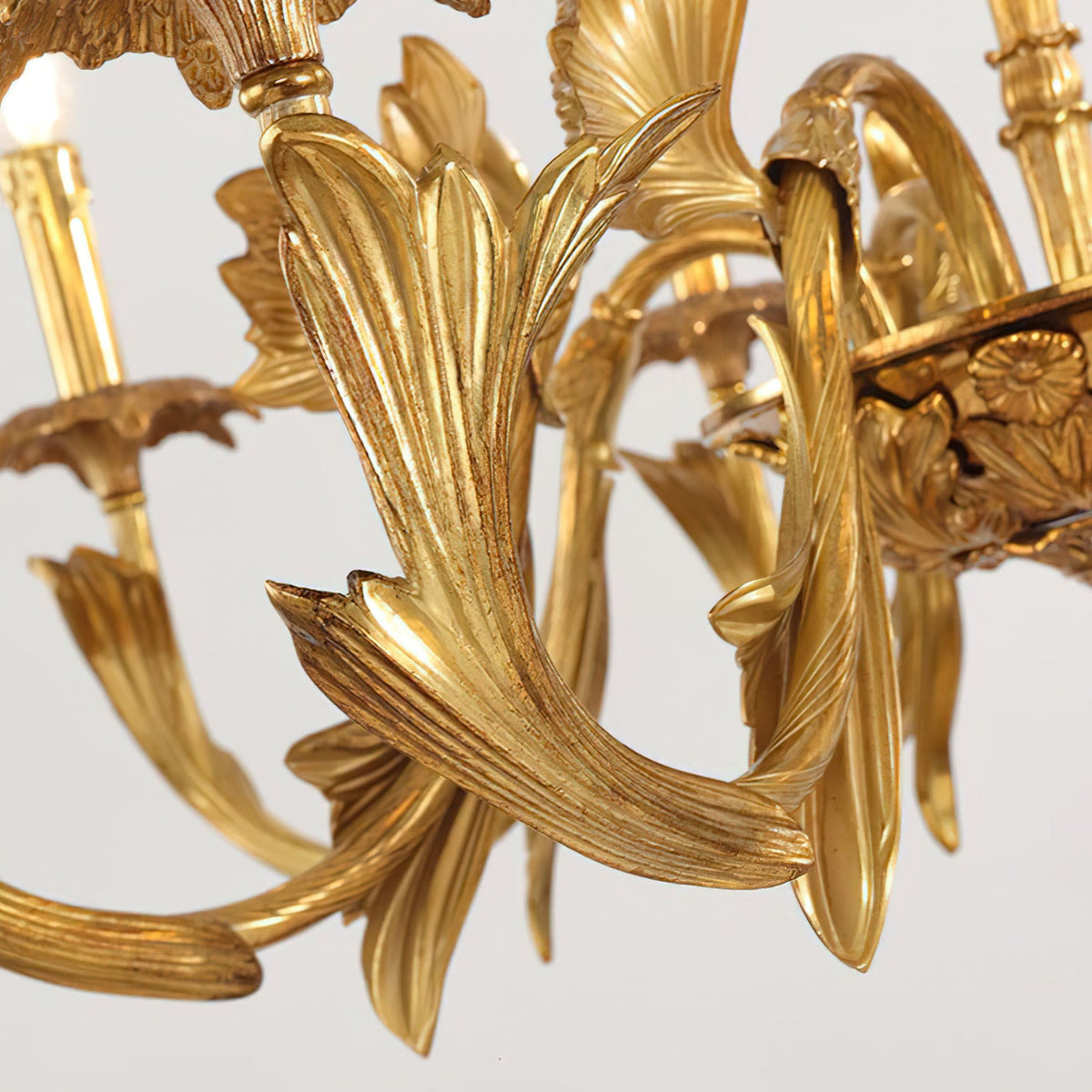 Close view of the sculpted, ribbed brass leaf on one arm of this Clérachic chandelier, with the central bowl beside it.