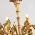 Close view of the reeded brass stem and two lit candle bulbs on this Clérachic chandelier.