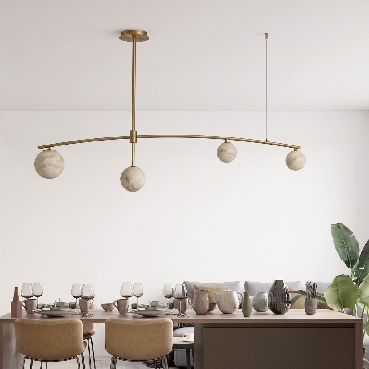 In brass, this Clérachic chandelier's arched bar stretches above a long table set with wine glasses and pottery.