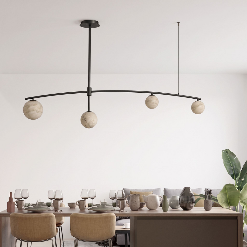 This Clérachic chandelier in matte black holds its ball shades over the same long table and a leafy plant.