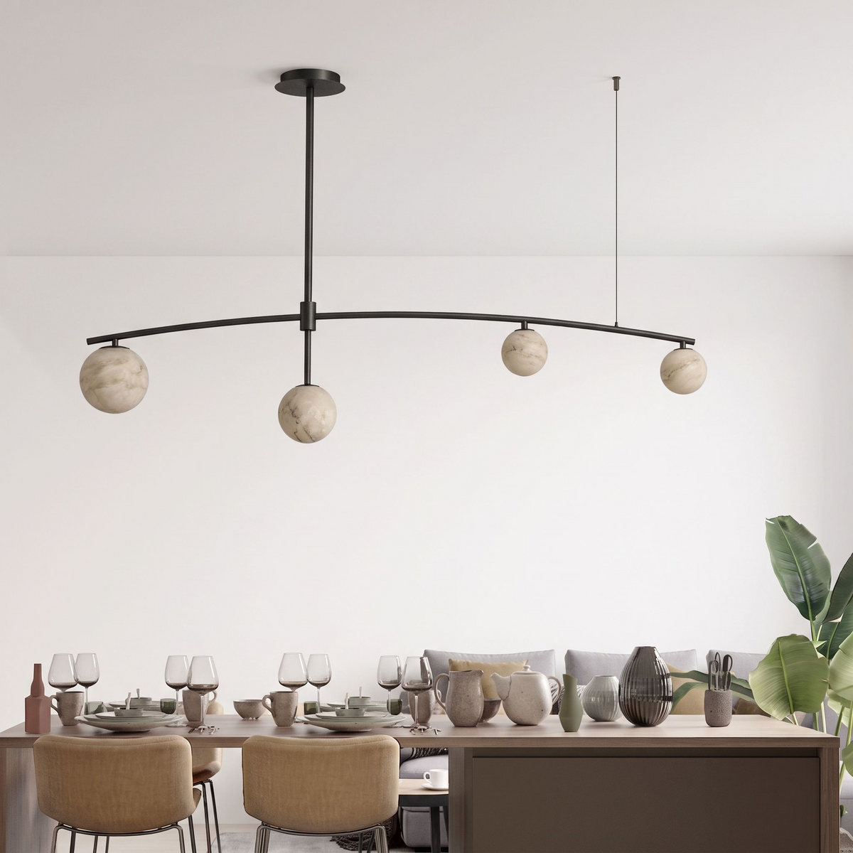 This Clérachic chandelier in matte black holds its ball shades over the same long table and a leafy plant.