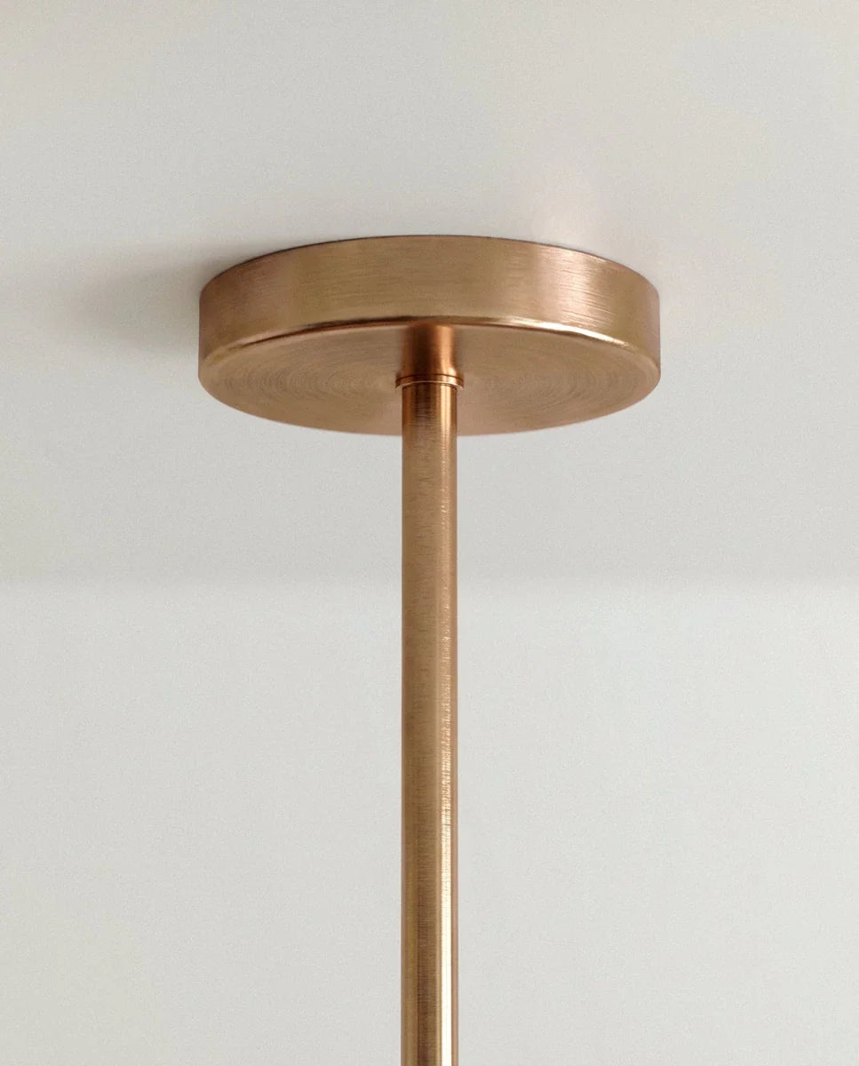 Clérachic close view of the brushed gold round ceiling canopy and slim stem that carry the branching rod chandelier.