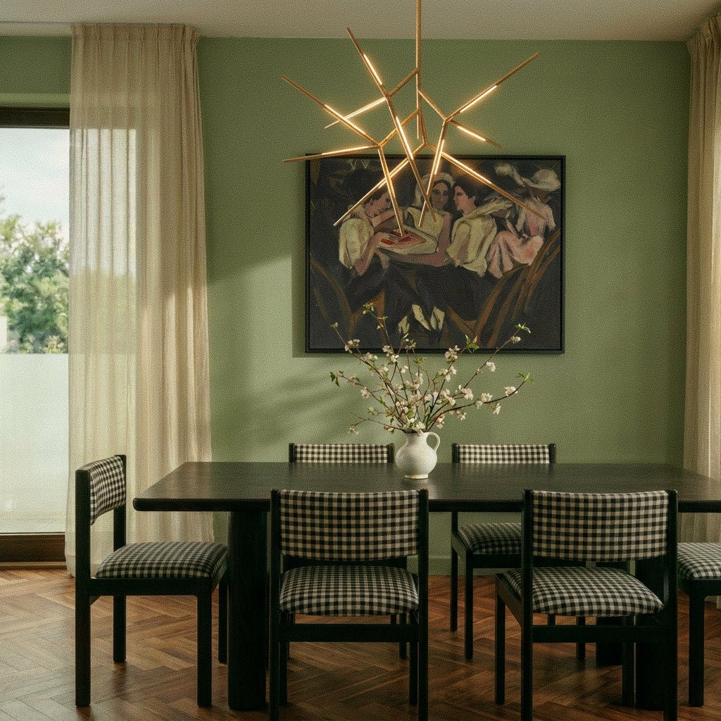 Clérachic gold rod chandelier lit above a dark dining table with gingham chairs, in a sage green room with herringbone floor.