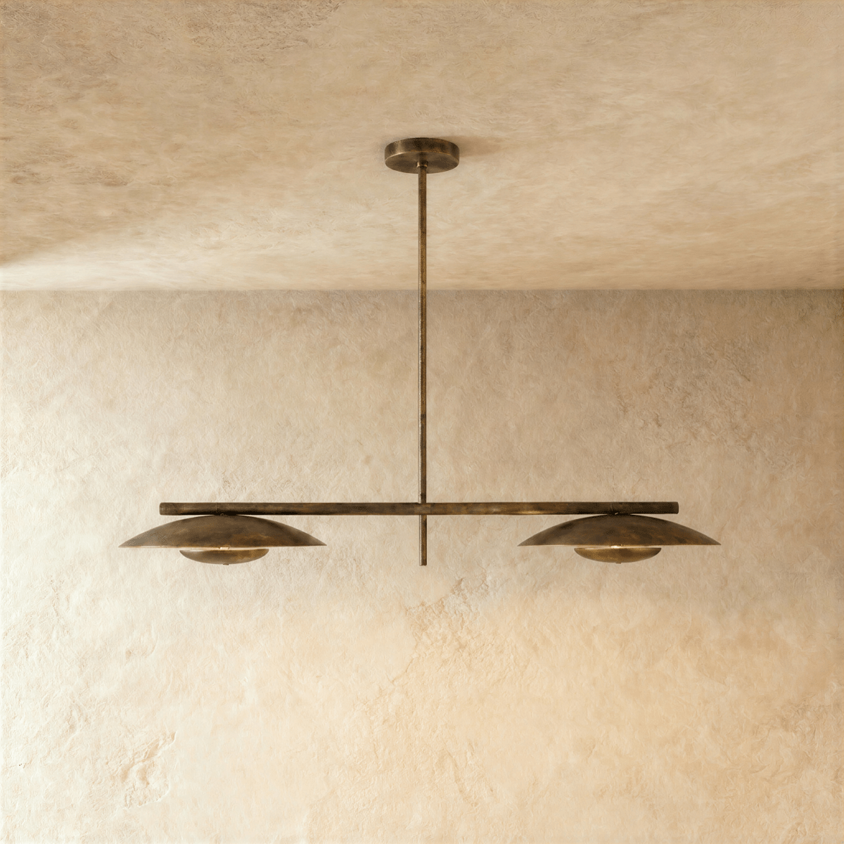 Clérachic chandelier in vintage brass with two angled disc shades suspended from a slim horizontal bar.
