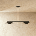 Clérachic chandelier in matte black, front view of the paired disc shades against a plaster wall.