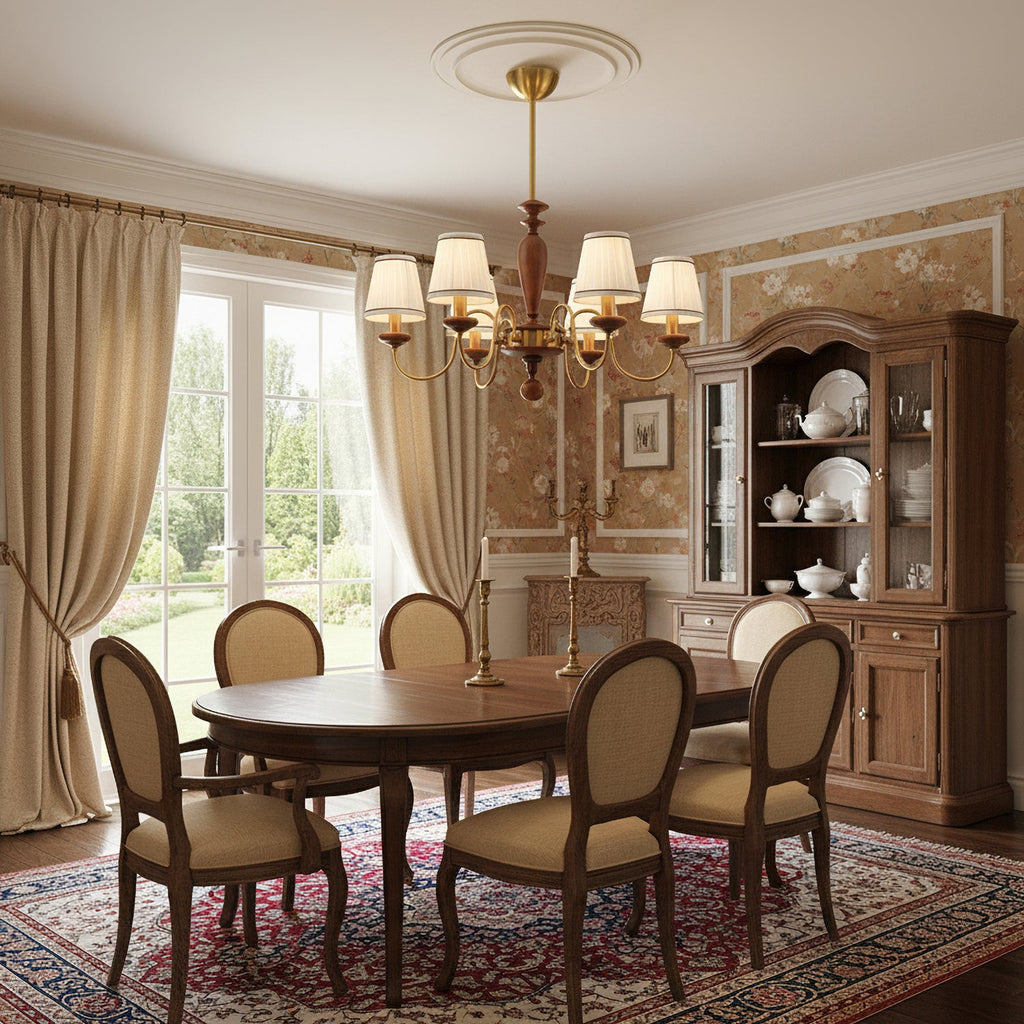 A Clérachic chandelier with pleated shades hanging over a round wooden dining table, with upholstered chairs and a glazed dresser behind.