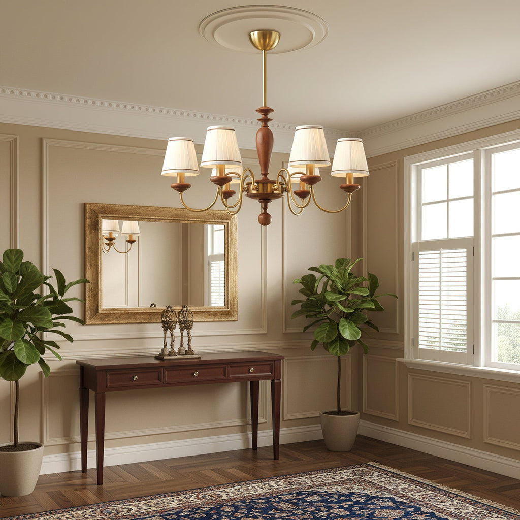 Clérachic chandelier hung from a ceiling rose in a panelled hallway, with a gilt mirror, a console table and two potted plants.