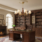Clérachic chandelier in a home study with floor-to-ceiling bookshelves, a leather chair and a wooden desk with a green lamp.