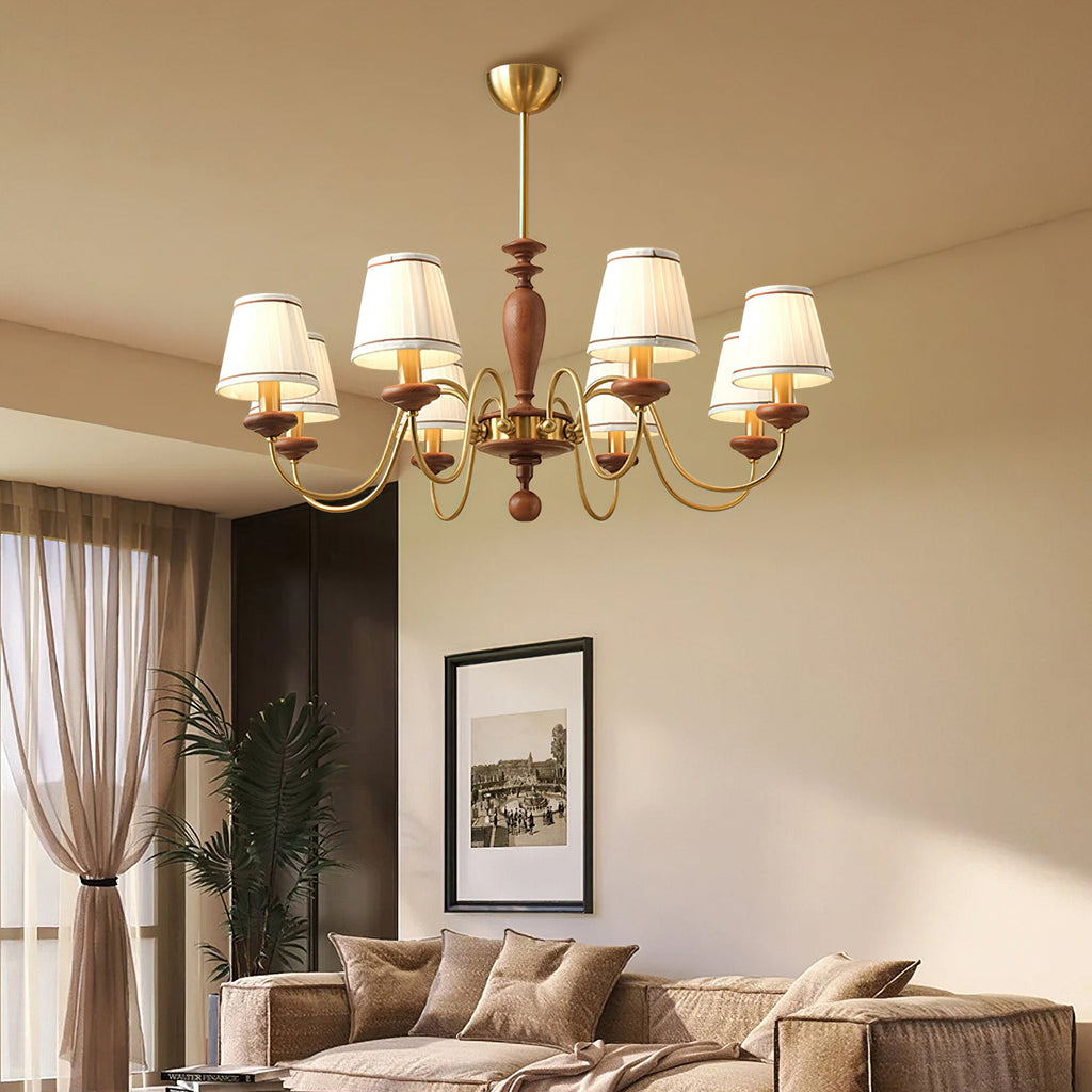 Clérachic chandelier in a warm-toned living room, its white pleated shades glowing above a sofa, a sheer curtain and a framed photo.