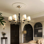 Chrome and black version of this Clérachic chandelier hung from a ceiling rose in a room with arched dark doors and a floor lamp.