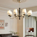 Clérachic chandelier in chrome and black, lit in a pale panelled room with a leather sofa and framed prints.