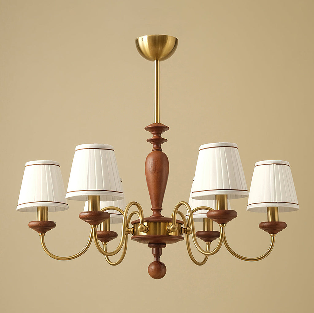 Gold and walnut Clérachic chandelier on a warm beige backdrop, six pleated shades on curved brass arms around a turned wooden stem.