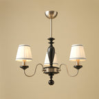 Three-light chrome and black Clérachic chandelier with S-curved arms and a black turned stem, photographed on a beige backdrop.