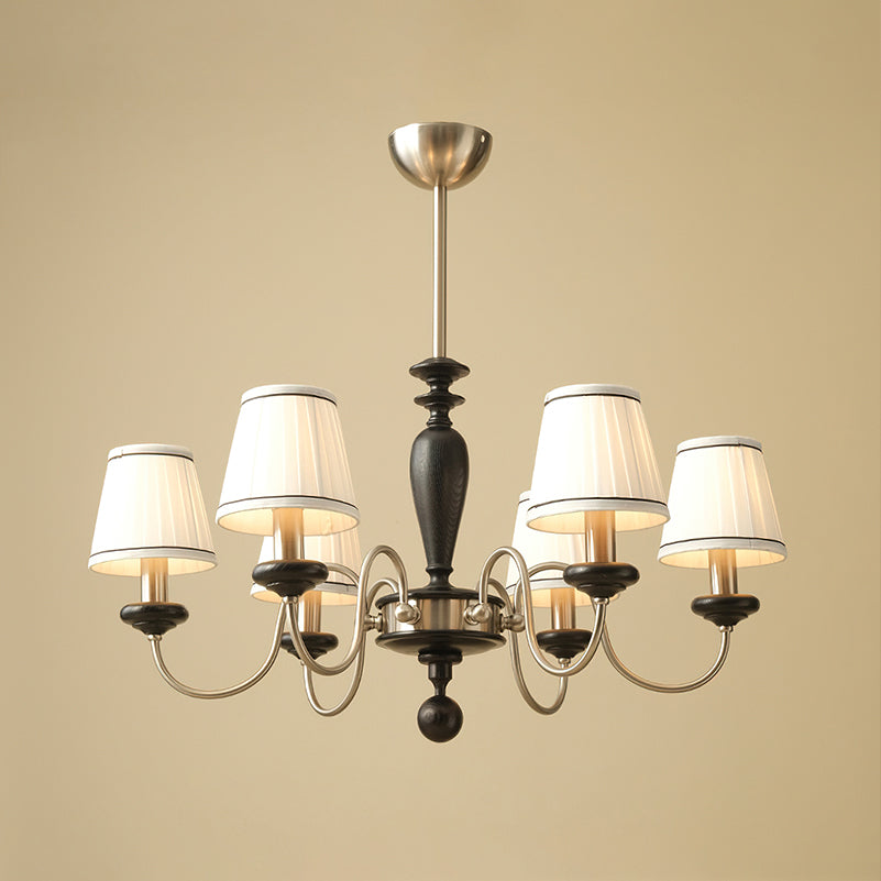 Chrome and black Clérachic chandelier with six lit shades and a black turned stem, on a plain sand-coloured background.