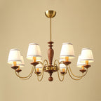Eight-light gold and walnut Clérachic chandelier, its two tiers of brass arms and pleated shades lit on a beige backdrop.