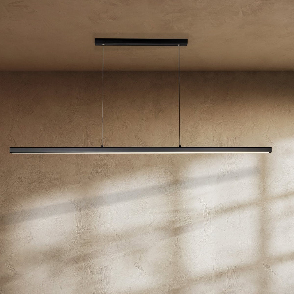 Clérachic slim black linear pendant hung from two fine cables over a textured clay-toned wall, with light along its lower edge.