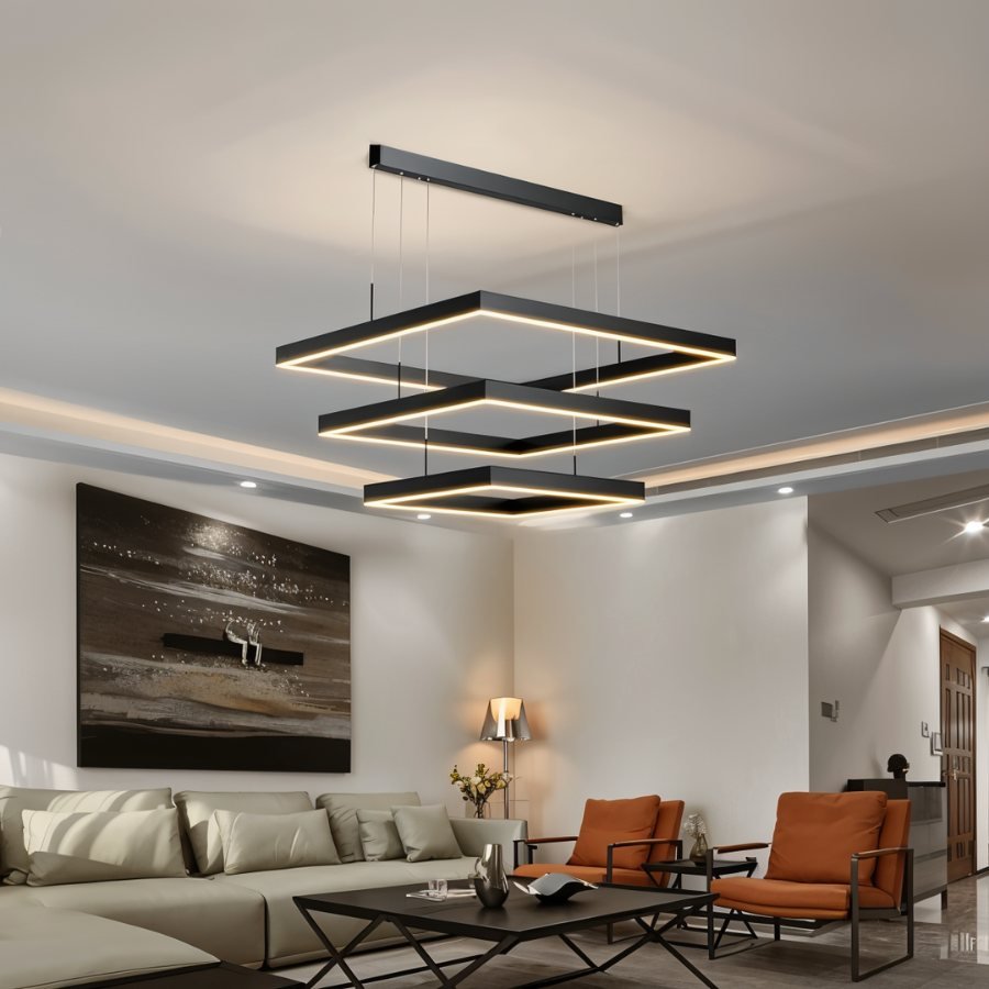 Clérachic three-tier black square LED chandelier hanging above a sofa and orange armchairs in a neutral lounge.