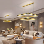 Clérachic gold square LED chandeliers, one two-tier and one single, lighting a dining and living area in warm tones.