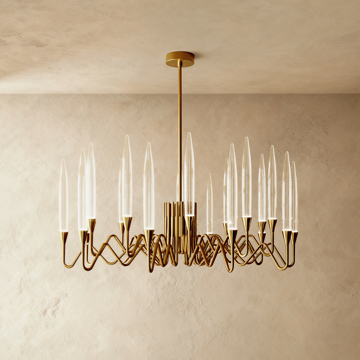 Clérachic round brass chandelier with slender clear bubbled glass shades on wavy arms, hung from a rod against a limewash wall.
