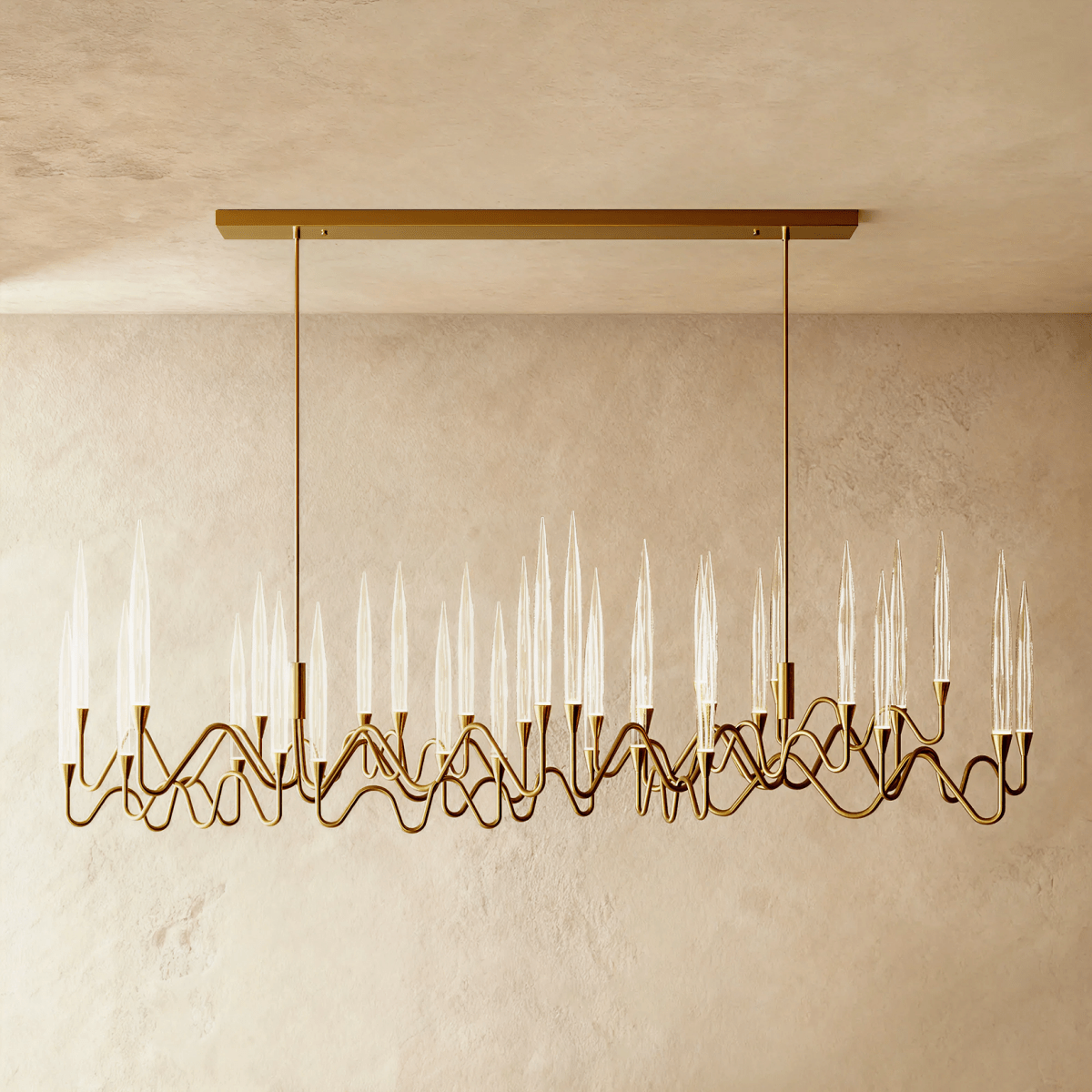 Clérachic long linear brass chandelier on two rods and a rectangular canopy, with many glass spikes over wavy arms, limewash wall behind.