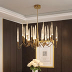 Clérachic round brass chandelier with lit glass shades in a dark panelled room, with white roses and a framed print beneath.