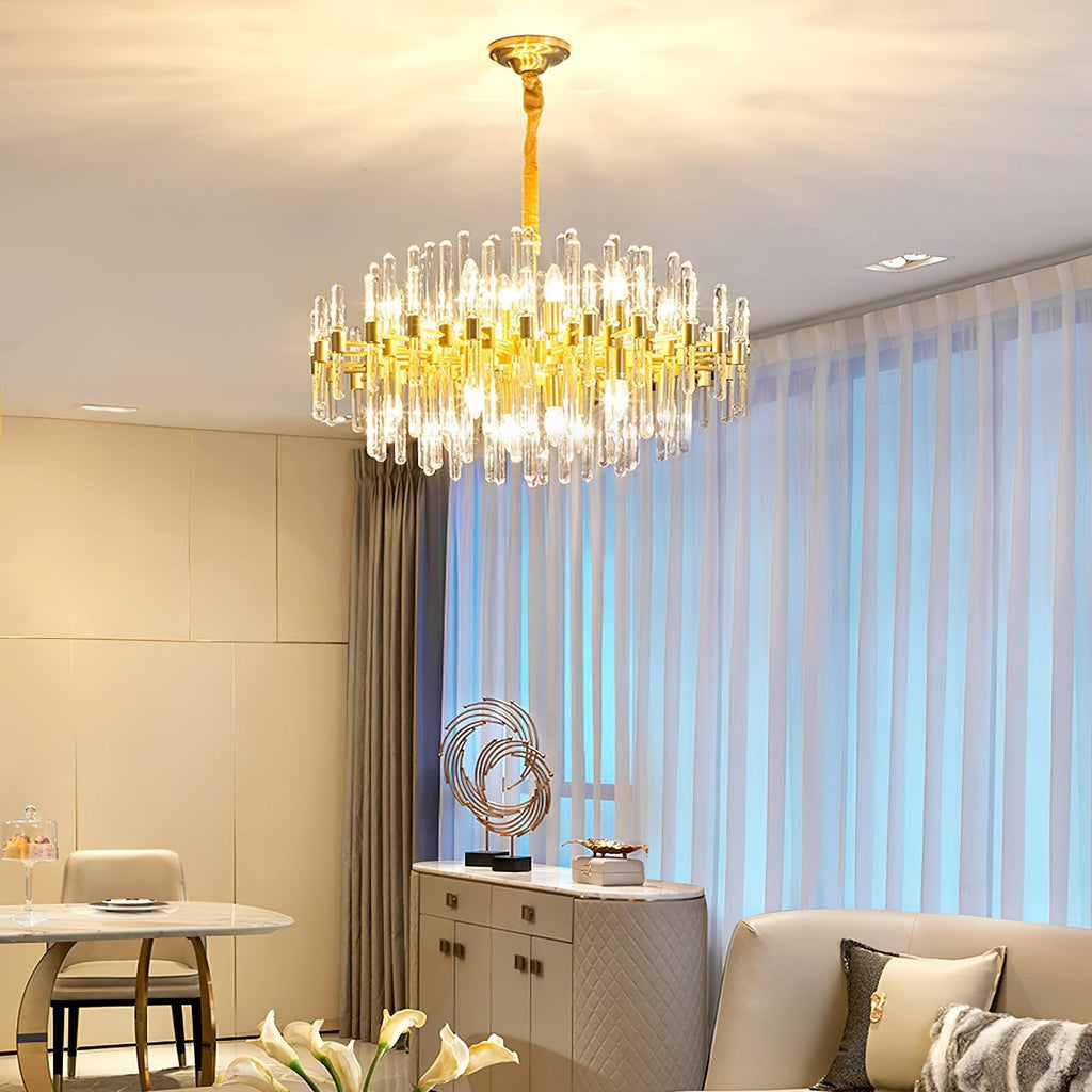 Warm light from this Clérachic brass chandelier fills a living and dining area, with sheer blue-tinted curtains and cream wall panels behind.