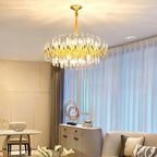 Warm light from this Clérachic brass chandelier fills a living and dining area, with sheer blue-tinted curtains and cream wall panels behind.