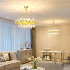 In a room with cream sofas and a dining table, two Clérachic glass-rod chandeliers hang at different distances under recessed spotlights.