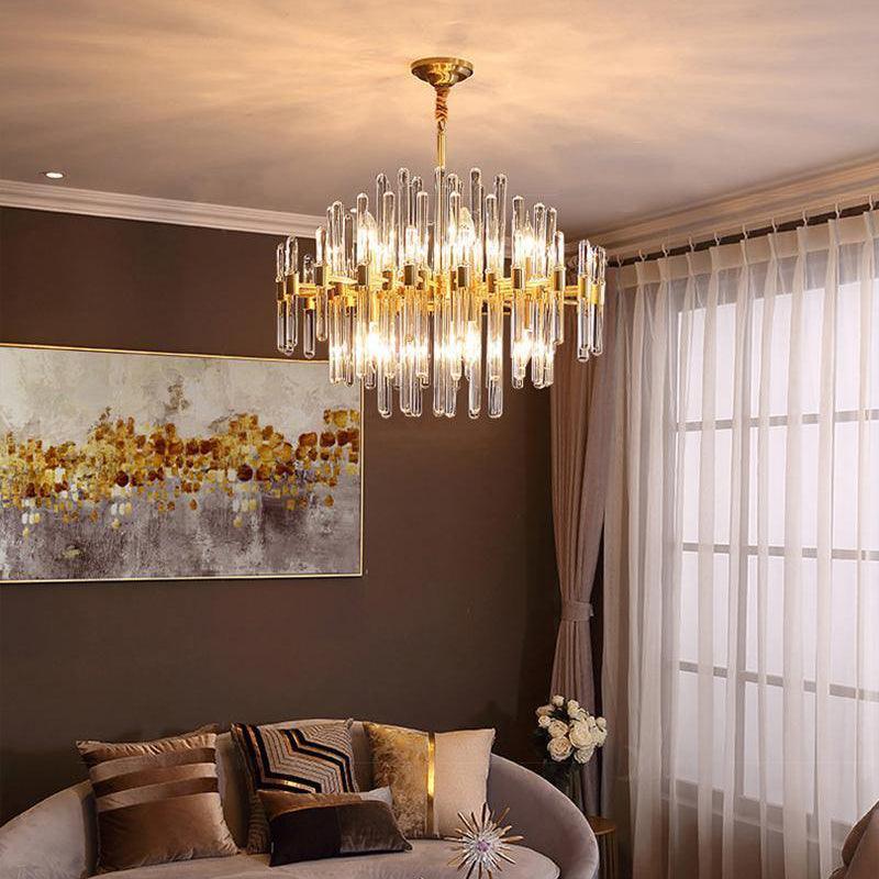 A Clérachic brass and glass rod chandelier lit above a velvet sofa in a brown-walled room, with a golden abstract painting and sheer curtains.