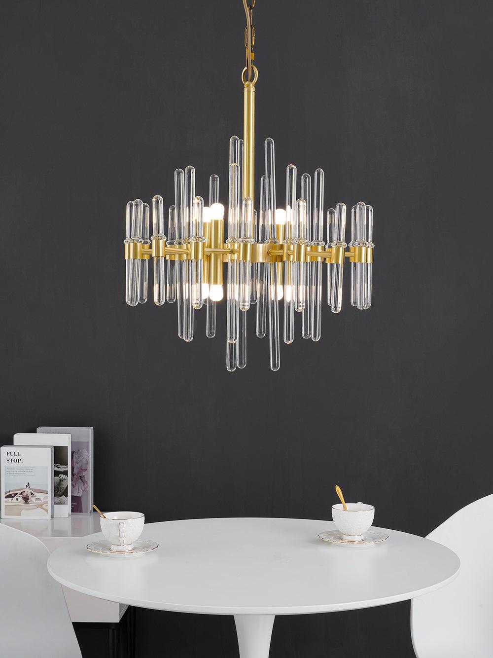 Clear glass rods and brass bars of this Clérachic chandelier set against a dark grey wall, above a round white table and cups.