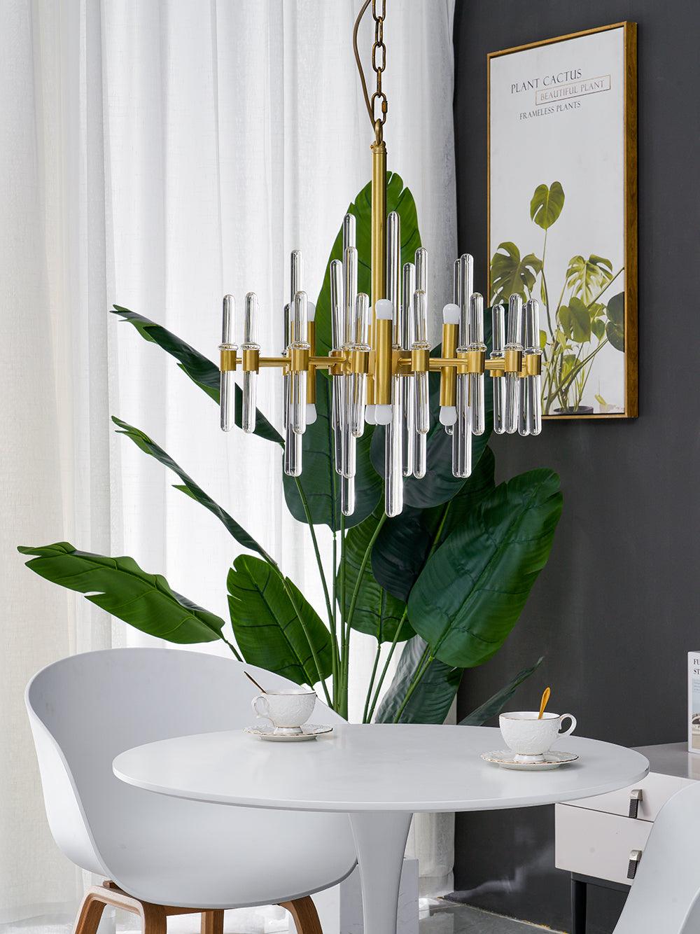 This smaller Clérachic chandelier hangs on a chain above a white table, with a large green leaf in front and a framed print behind.