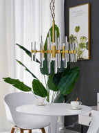 This smaller Clérachic chandelier hangs on a chain above a white table, with a large green leaf in front and a framed print behind.