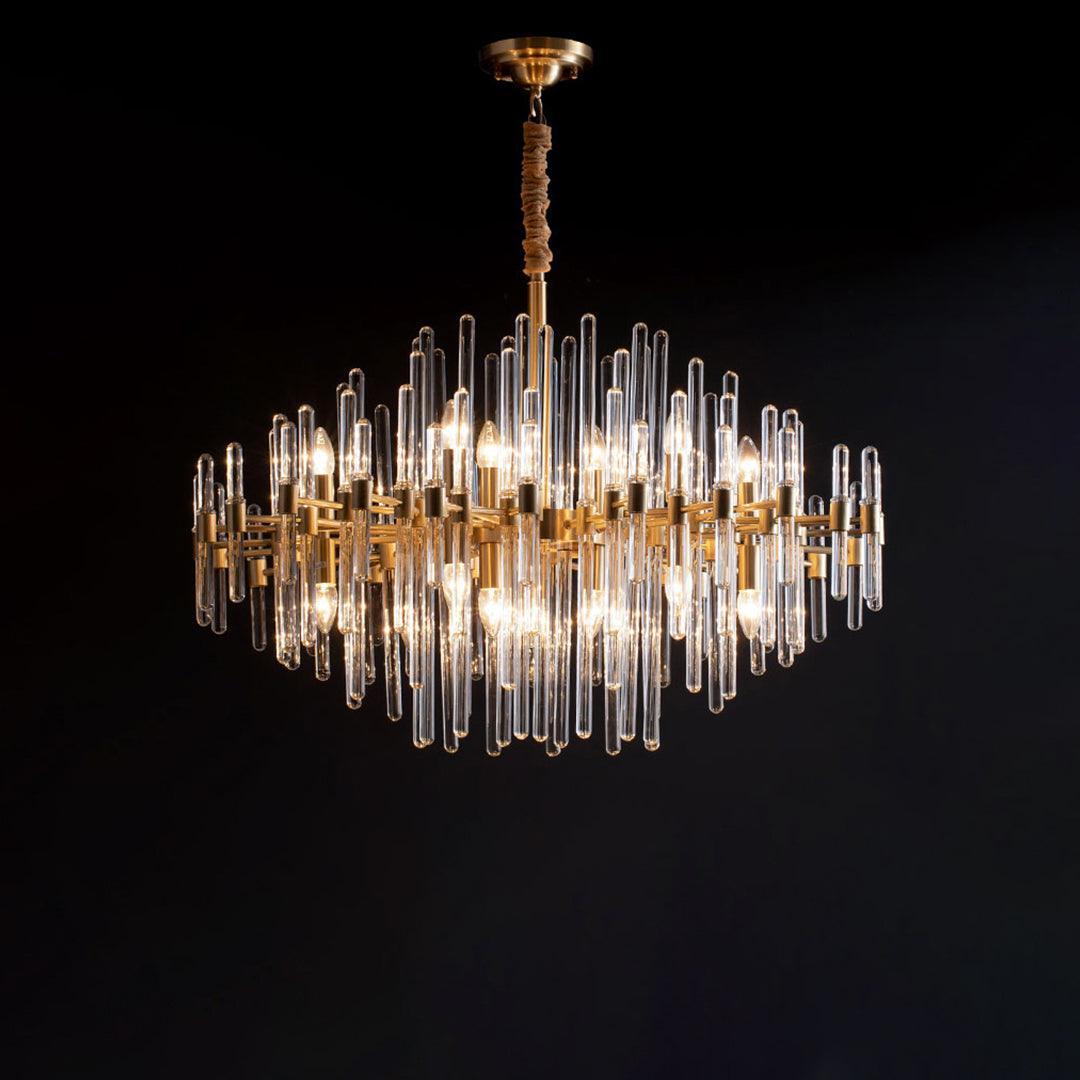 Against a black backdrop, this Clérachic chandelier shows its brass arms, clear glass rods and candle-style bulbs in a diamond-shaped outline.