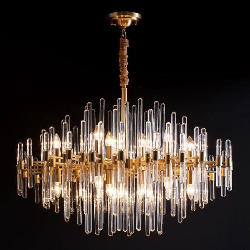 Low, wide view of this Clérachic brass chandelier on black, with several tiers of clear glass rods around candle-style bulbs.