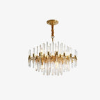 A Clérachic brass chandelier hanging from a ceiling plate on a twisted gold-brown cover, with clear glass rods, on a plain light backdrop.