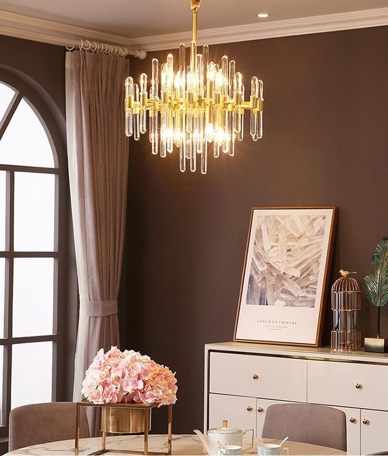 This Clérachic chandelier hangs in a dining space with an arched window, a framed print and a sideboard topped with pink flowers.