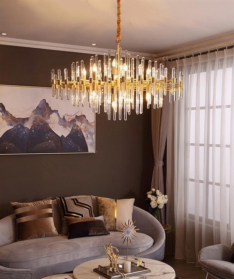 Seen from below, this Clérachic chandelier lights a brown living room, with a mountain painting, sheer curtains and a curved sofa.