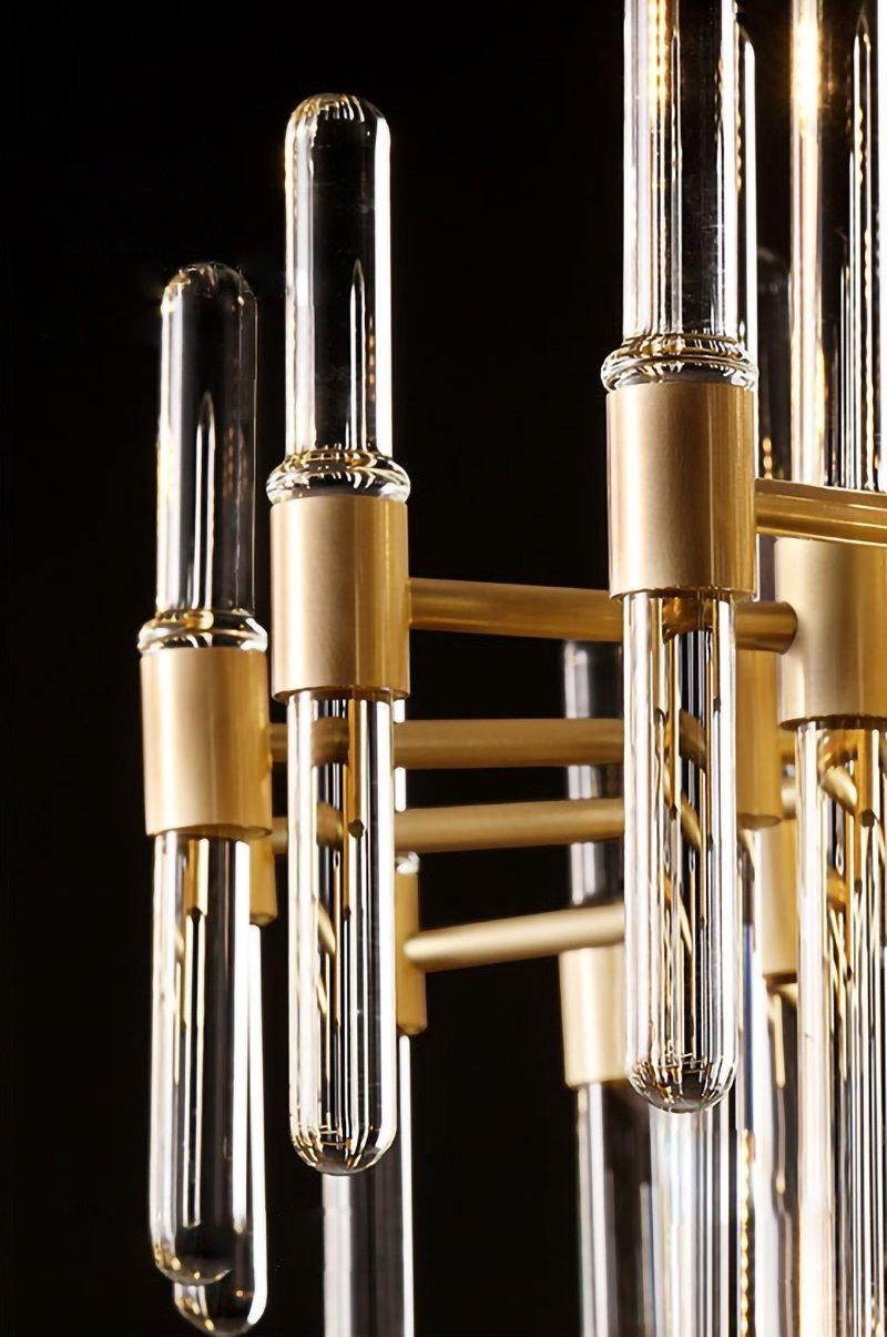 Close view of brass sockets holding clear glass rod ends, with rounded tips, on this Clérachic chandelier against a dark backdrop.