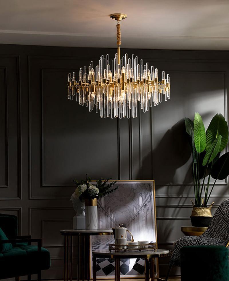 Against grey wall panelling, this Clérachic chandelier hangs above a side table with a framed picture, a plant and a tray with teapot.