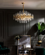 Against grey wall panelling, this Clérachic chandelier hangs above a side table with a framed picture, a plant and a tray with teapot.