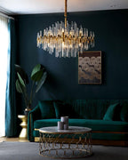 Above a green velvet sofa and a gold-framed round table, this Clérachic chandelier hangs against a deep teal wall.