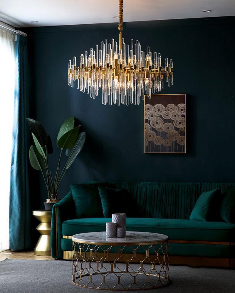 Above a green velvet sofa and a gold-framed round table, this Clérachic chandelier hangs against a deep teal wall.