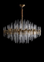 Straight-on view of this Clérachic chandelier on black, with its brushed brass frame, clear glass rods and covered hanging chain.