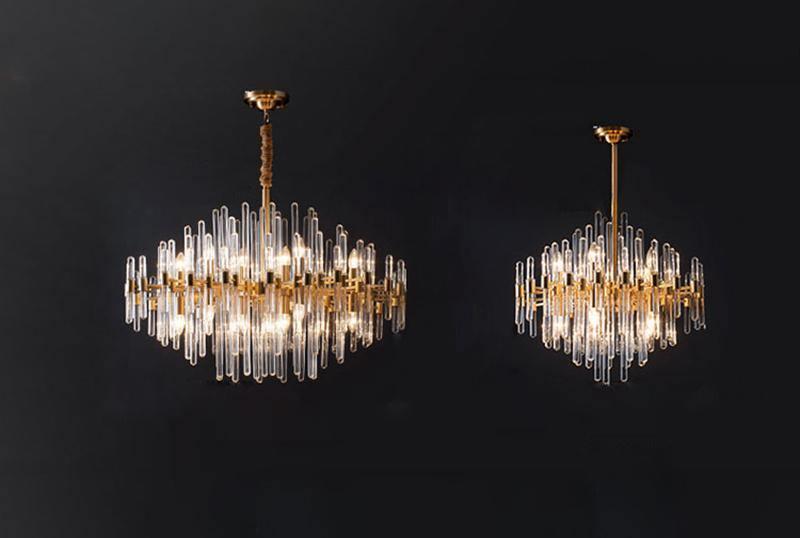 Two sizes of this Clérachic chandelier side by side on a black backdrop, both with clear glass rods and brushed brass frames.
