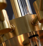 Close view of the brushed brass ring and angled arms at the centre of this Clérachic chandelier, with glass rods below.