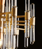 Close view of brass sockets, horizontal bars and clear glass tubes on this Clérachic chandelier, with a bulb inside one tube.